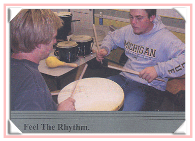 Two men playing a single drum togethr.
