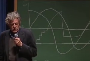 Author Kurt Vonnegut standing in front of a chalk board with some diagrams behind him. 